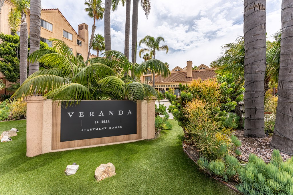a sign that says veranda with palm trees in the background