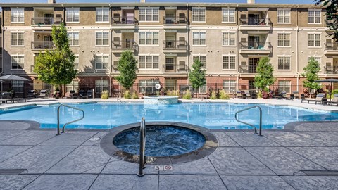 A large swimming pool in front of a multi-story apartment building.