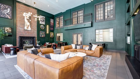 A living room with a brown leather couch and a fireplace.