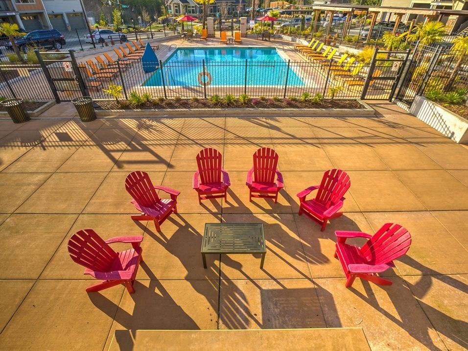 a group of red chairs sitting around a table near a swimming pool