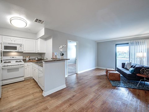 A kitchen with white appliances and wooden floors.