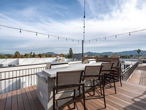 A balcony with chairs and a table overlooking a pool and trees.