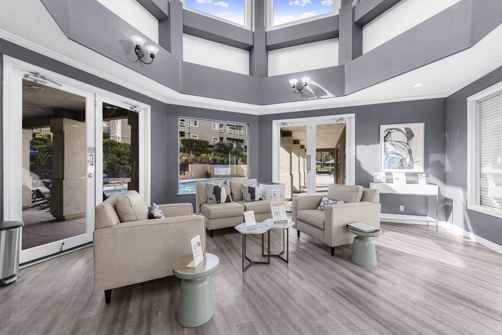 A living room with a large window and a view of a pool and buildings outside.