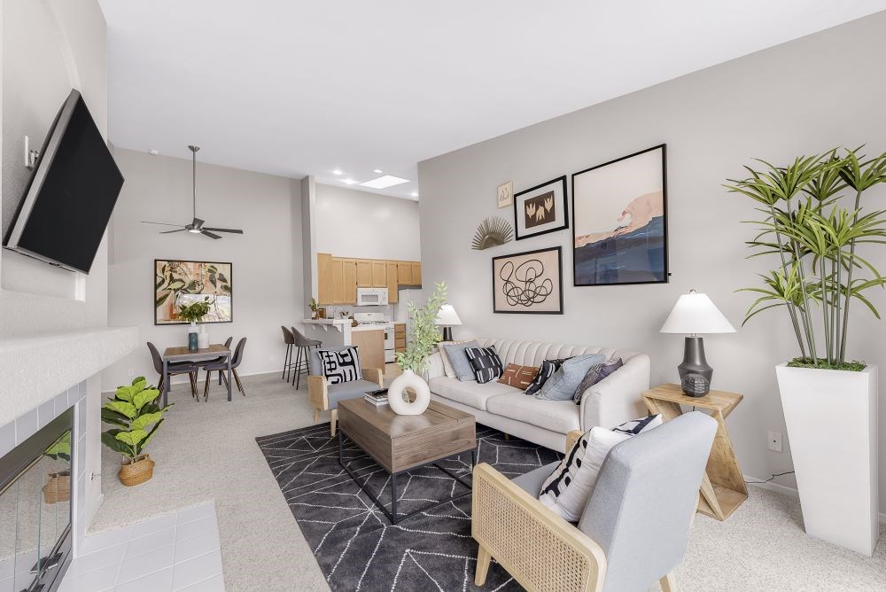 A living room with a white couch, a coffee table, and a television.