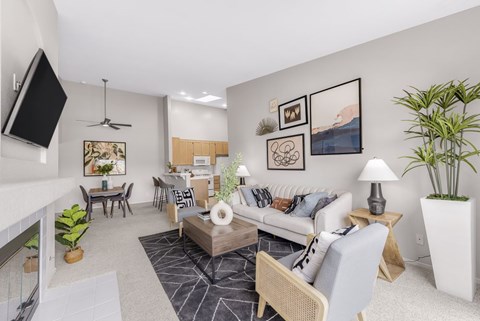 A living room with a white couch, a coffee table, and a television.