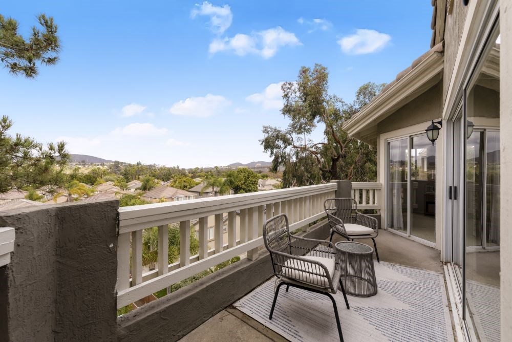 A patio with a table and chairs overlooking a mountainous landscape.