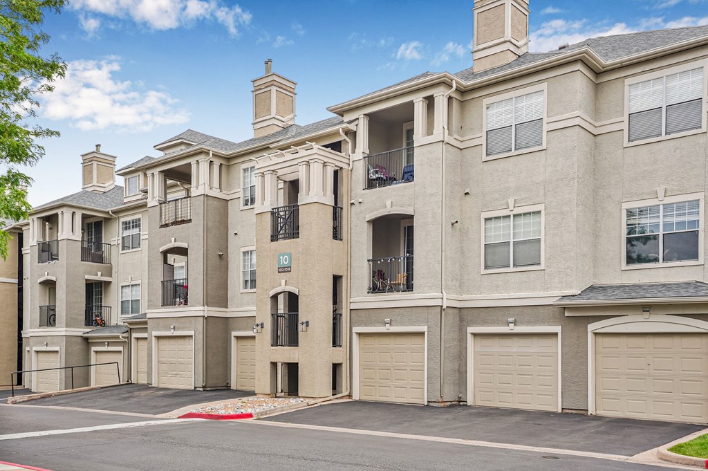 A large, multi-story residential building with a red brick facade and multiple garage doors.