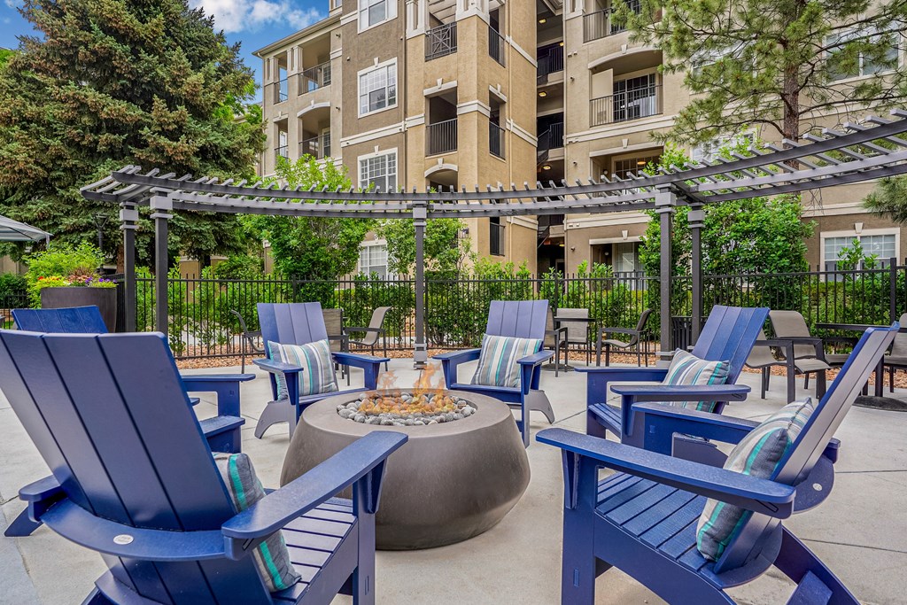 A patio with blue chairs and a fire pit.