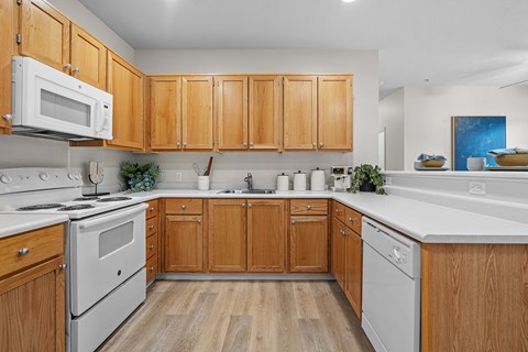 an empty kitchen with white appliances and wooden cabinets