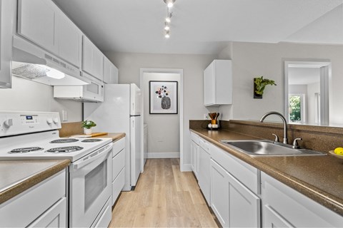 a kitchen with white cabinets and white appliances and a sink