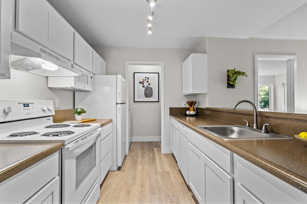 a kitchen with white cabinets and white appliances and a sink