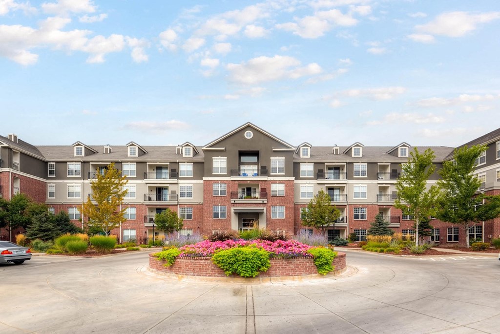 an exterior view of an apartment building with a circular driveway at The Viridian Apartments, Greenwood Village, CO, 80111