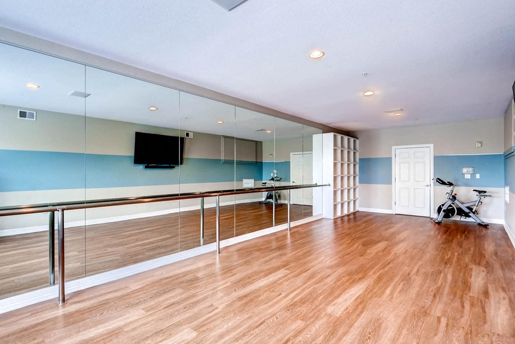 a workout room with mirrored walls and a wood floor at The Viridian Apartments, Colorado