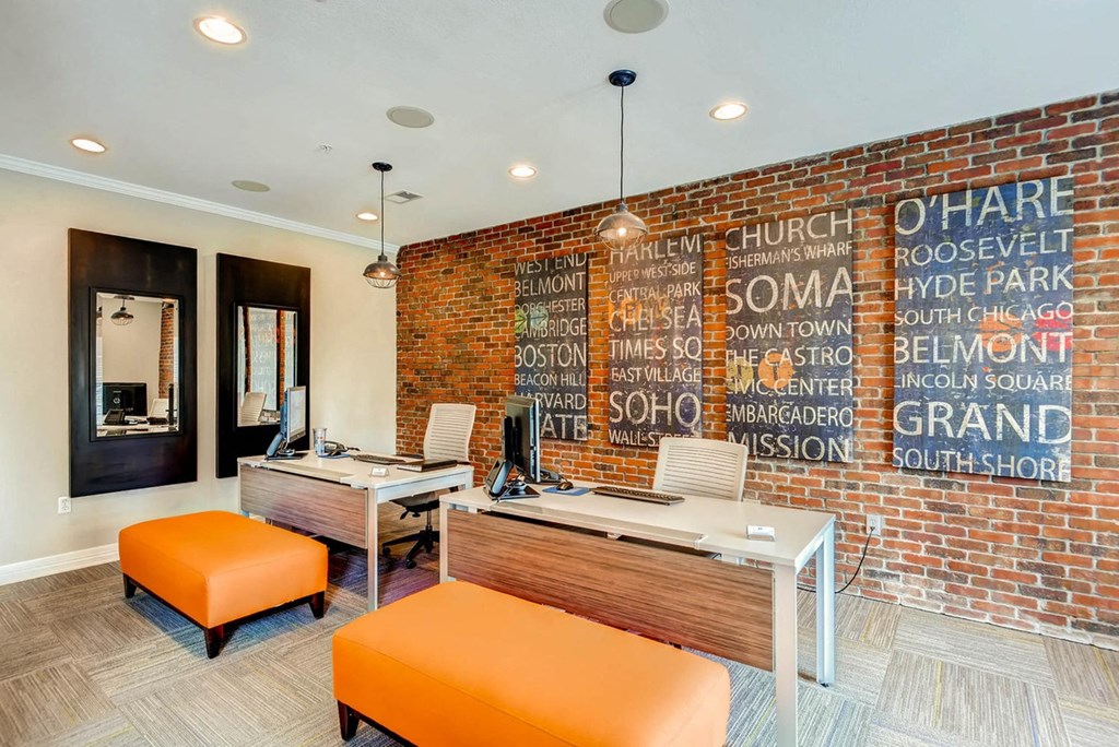 a brick wall in an office with two desks and orange chairs at The Viridian Apartments, Colorado, 80111