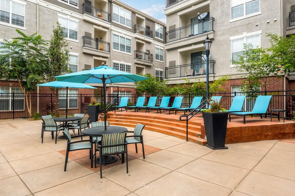 a patio with tables and chairs and umbrellas at an apartment building at The Viridian Apartments, Greenwood Village