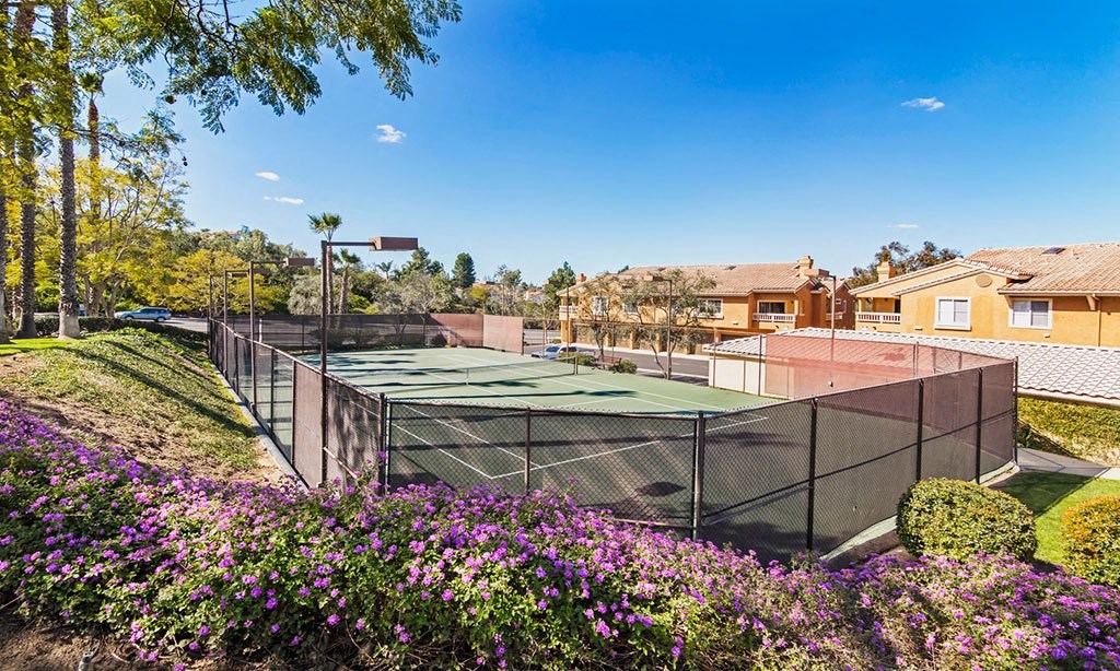 a tennis court with houses in the background