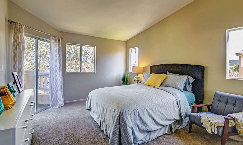 a bedroom with a bed and a chair and a window