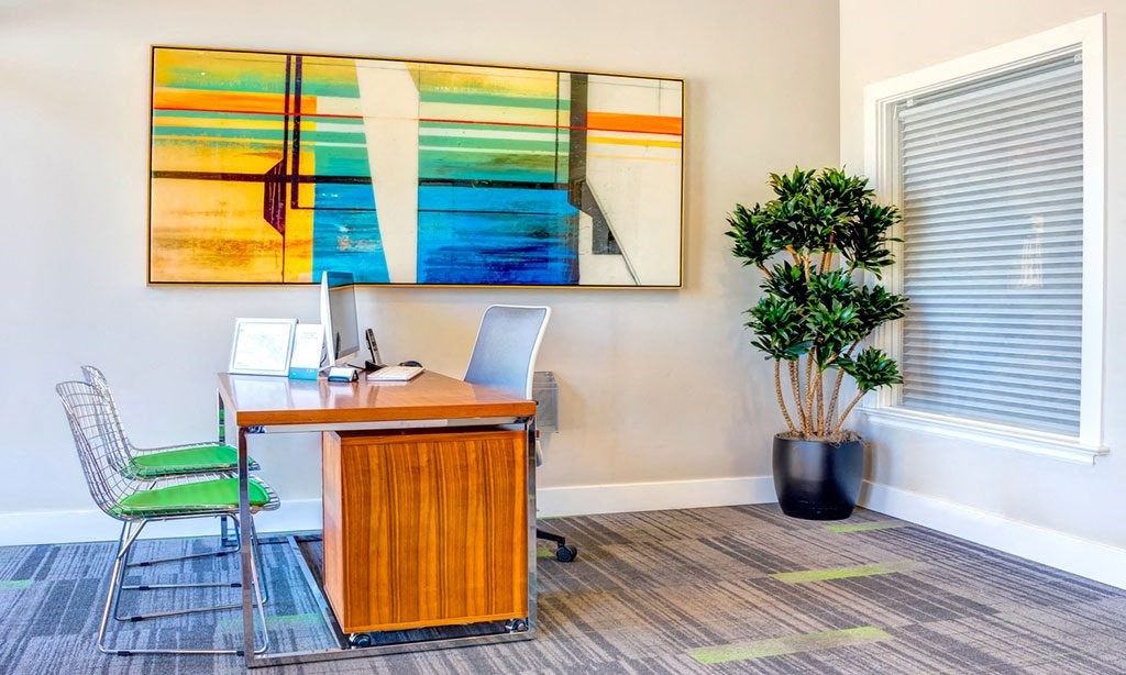 an office with a desk and a painting on the wall