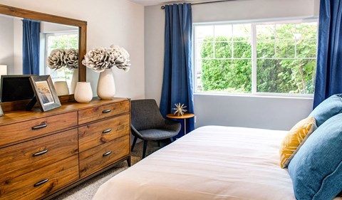 a bedroom with a bed and a dresser and a window