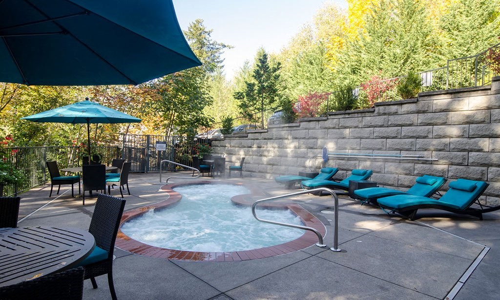 a jacuzzi in a backyard with chairs and an umbrella