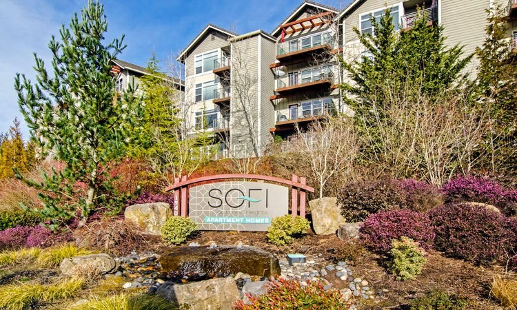 a sign in front of a building with trees and bushes