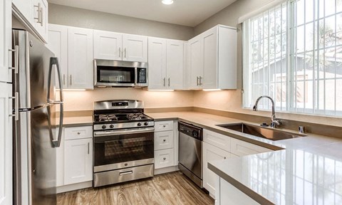 a kitchen with white cabinets and stainless steel appliances