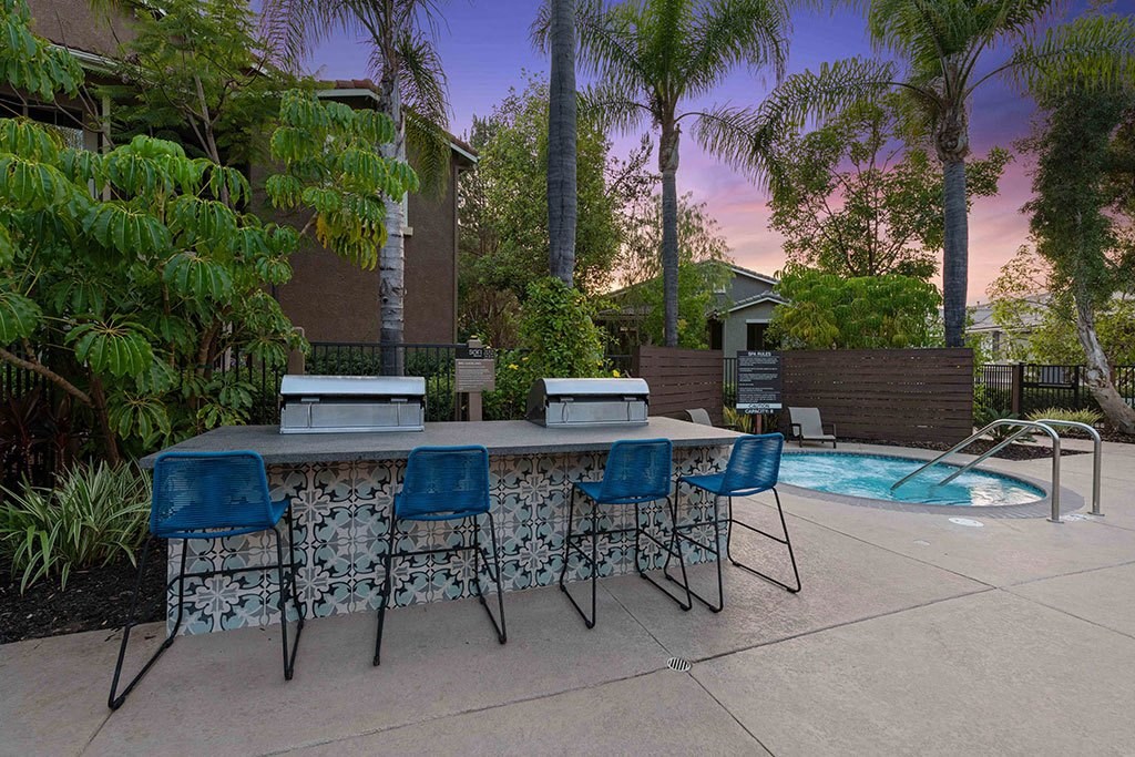 a patio with a bar and chairs and a pool