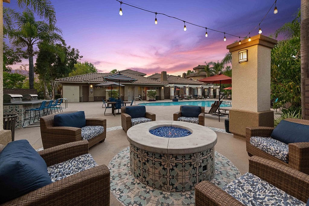 a patio with a fire pit and chairs and a pool