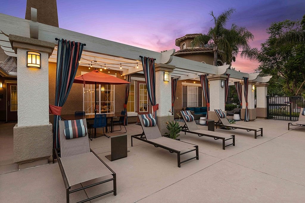 a patio with lounge chairs and umbrellas at dusk