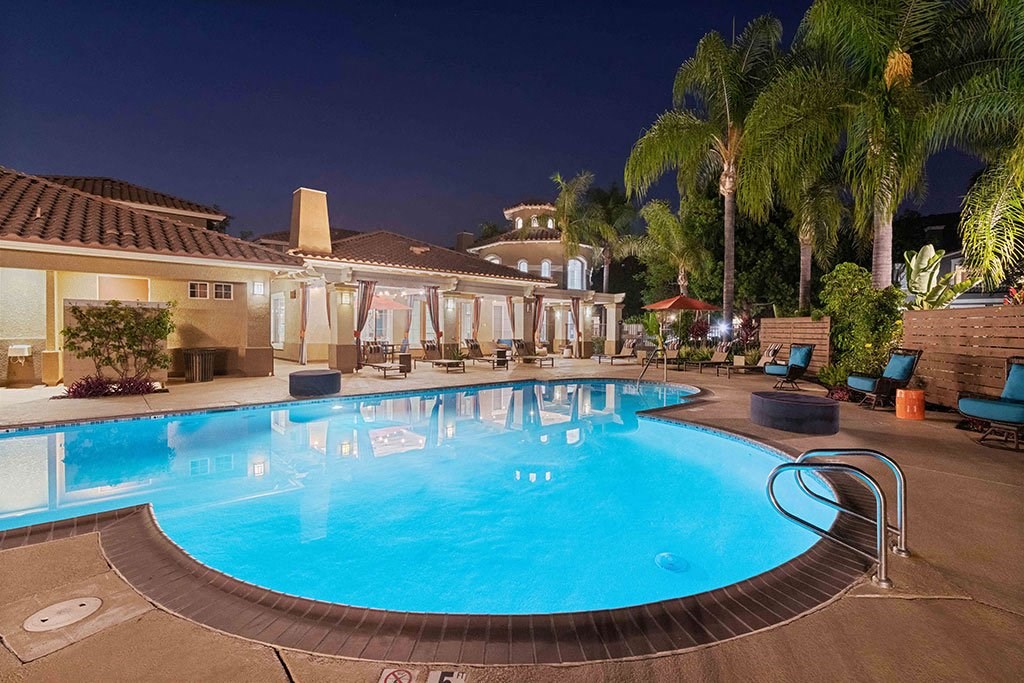 a large swimming pool at night at a hotel with palm trees