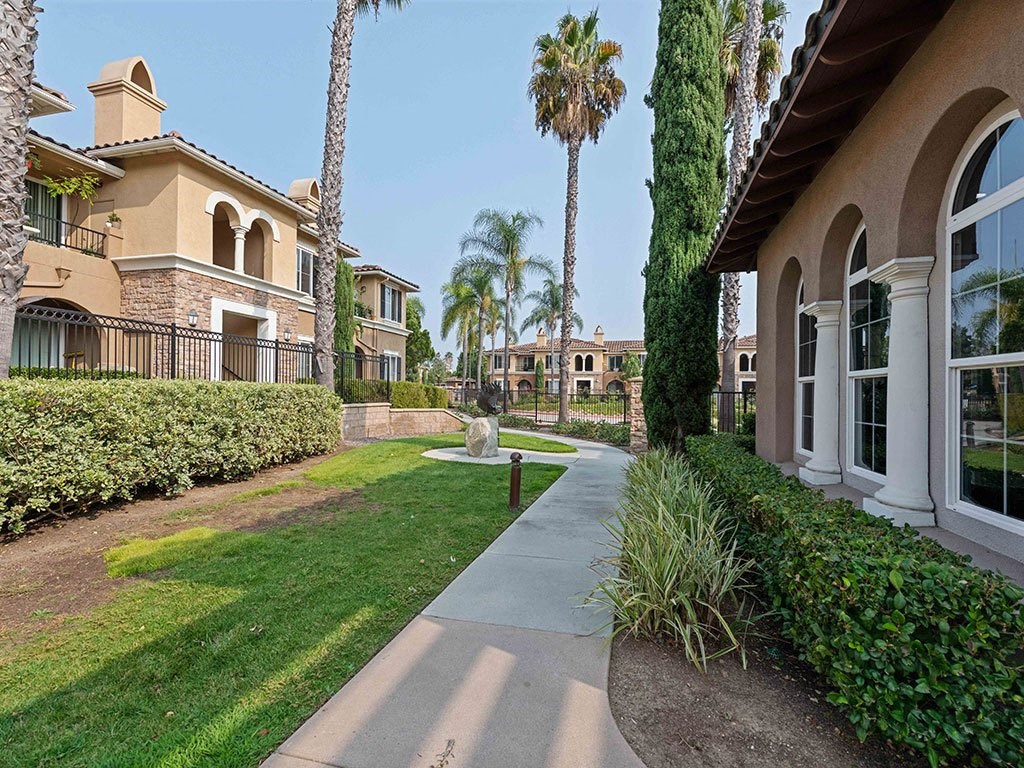 a sidewalk in front of a house with palm trees