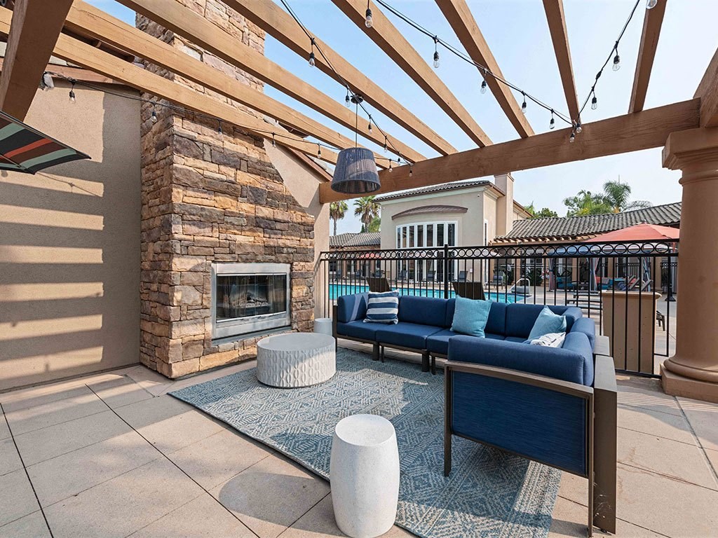 a covered patio with couches and a fireplace