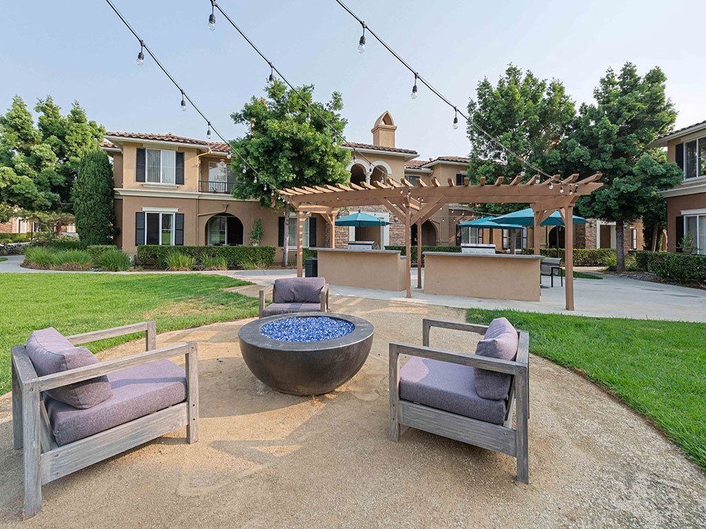 a patio with chairs and a fire pit in front of a house