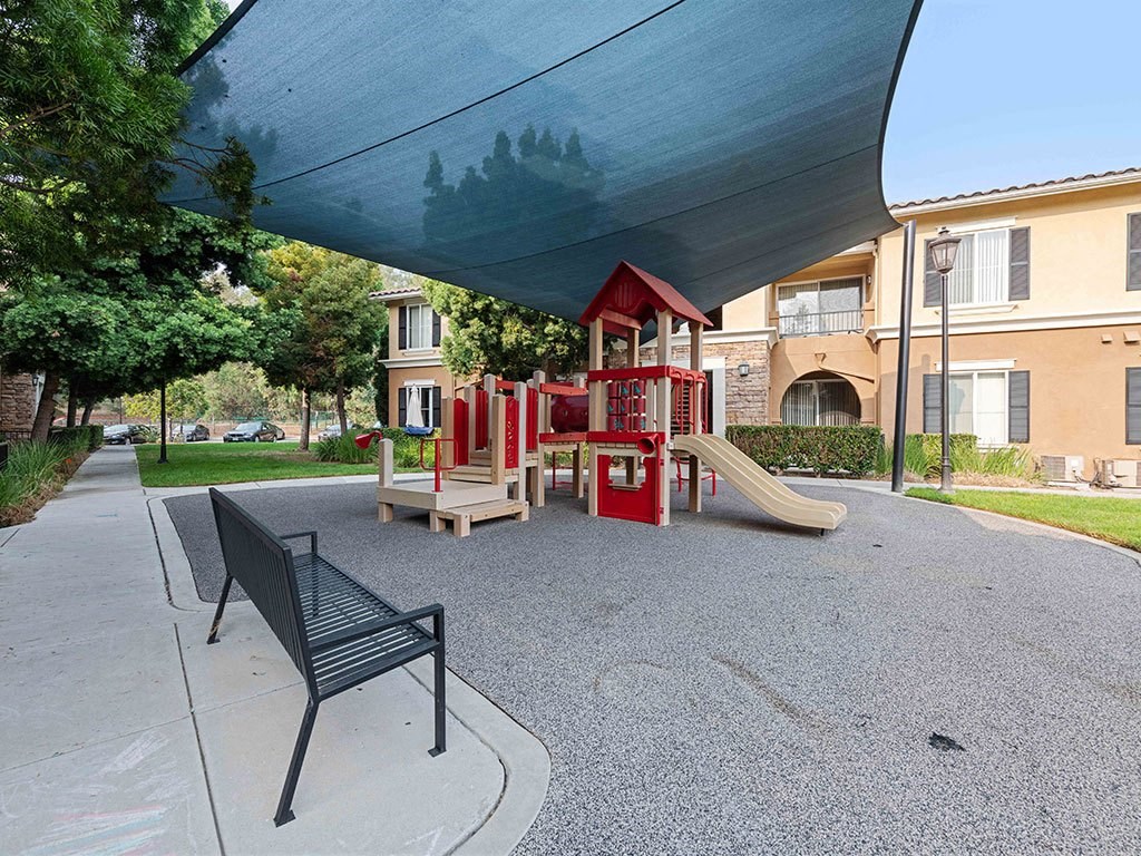 a playground with a red swing set and a bench