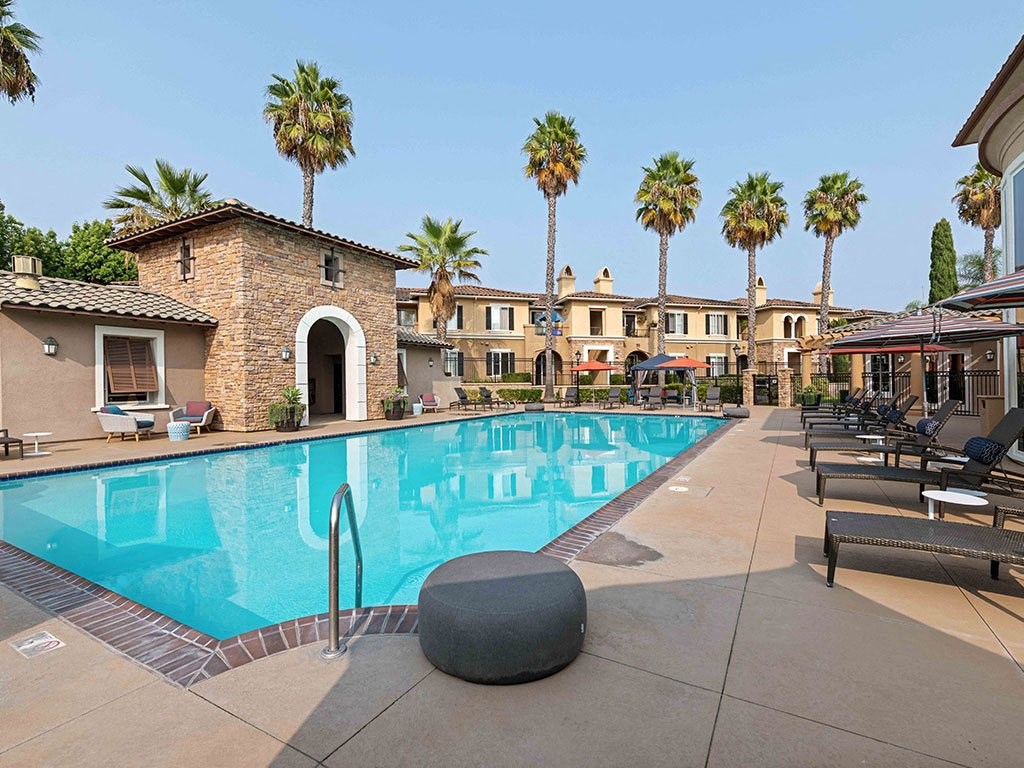 a swimming pool with palm trees in front of a hotel