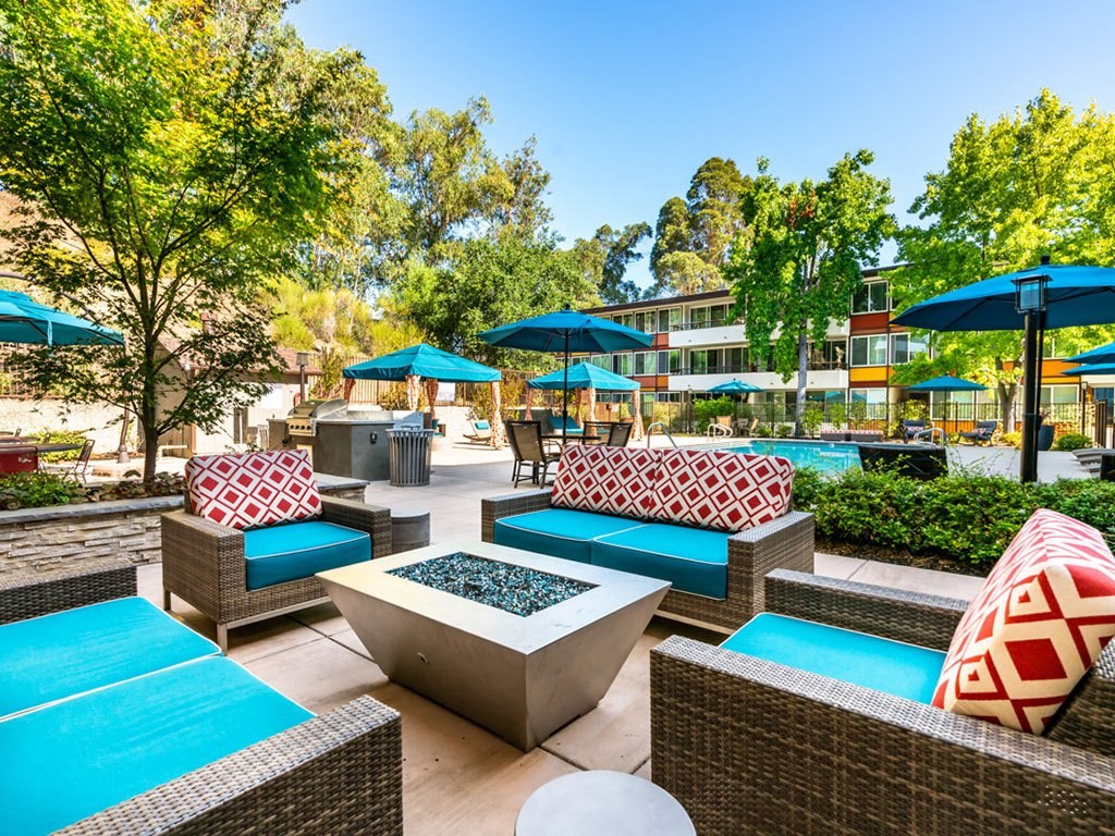 a lounge area with couches and chairs and umbrellas