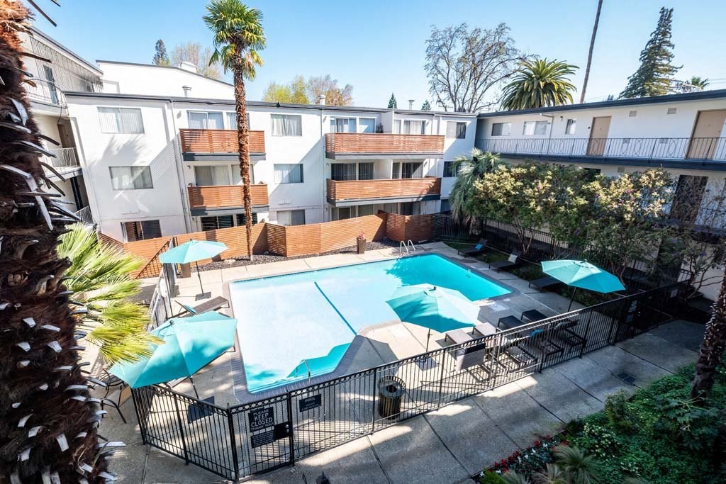 a resort style swimming pool with umbrellas in an apartment building