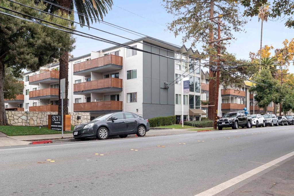 a city street with cars parked in front of an apartment building