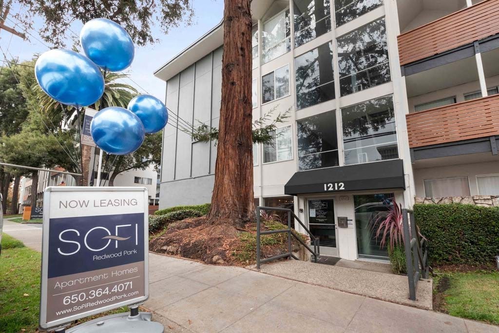 a sign in front of a building with blue balloons