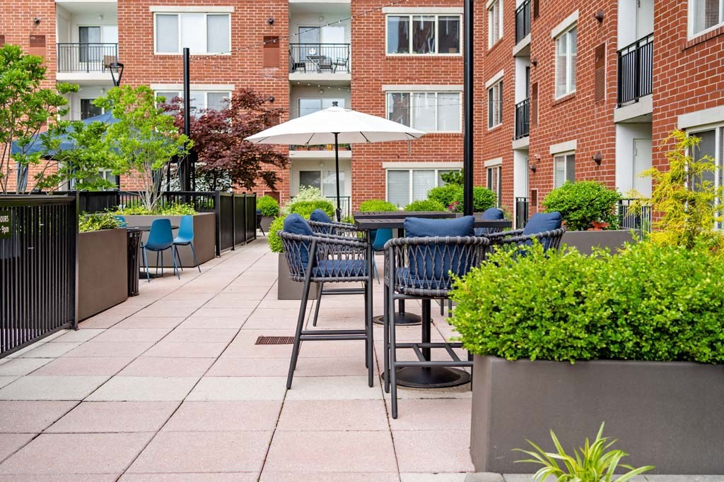 an outdoor patio with tables and chairs and a umbrella