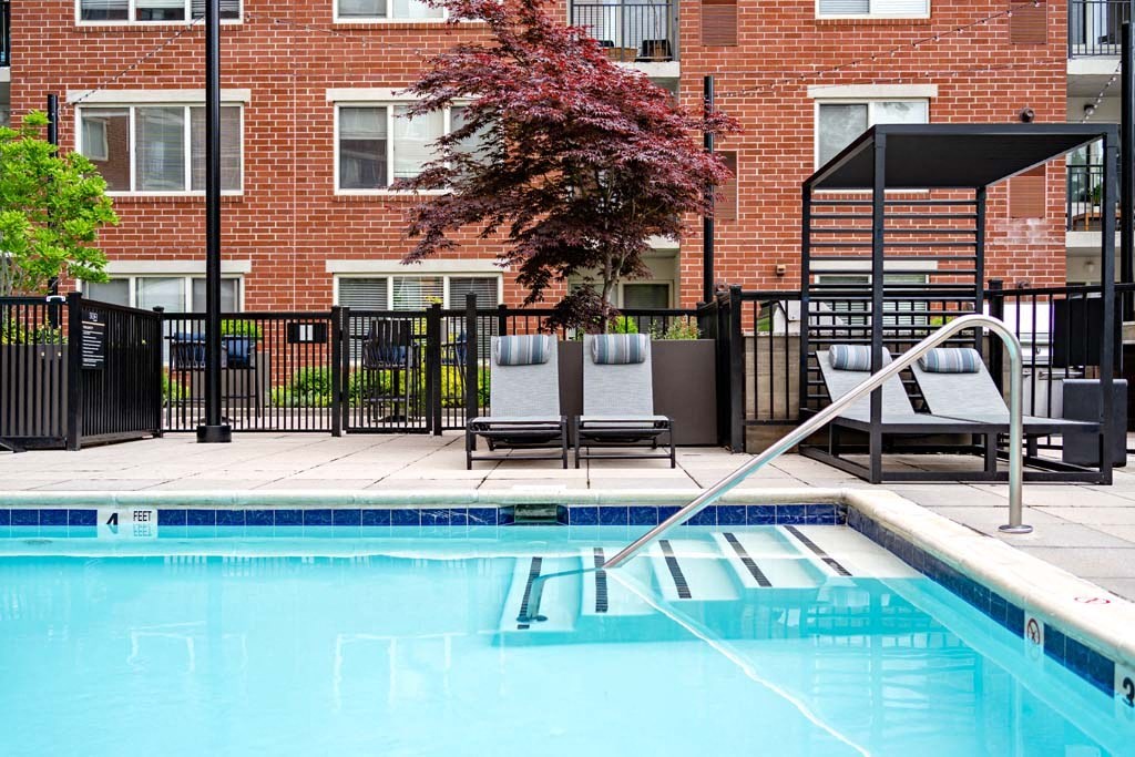 a swimming pool with two chairs and a building in the background