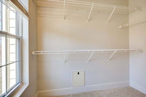 a closet in a room with white walls and a window
