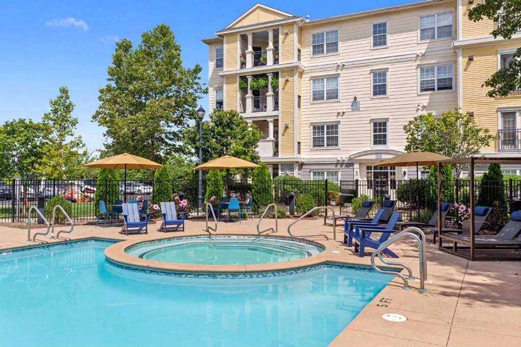 a swimming pool with chairs and a building in the background