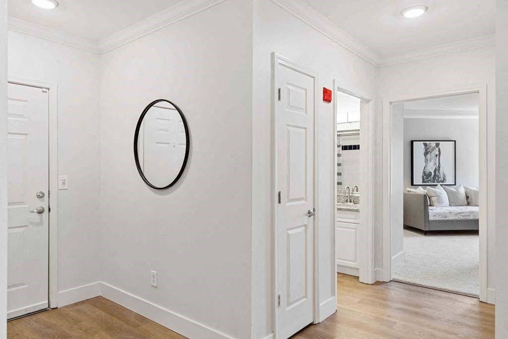 a white hallway with a mirror on the wall and a door to a living room