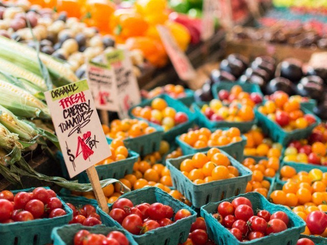 a display of tomatoes and other fruits and vegetables in baskets