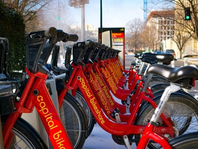 a row of red bikes parked next to a street