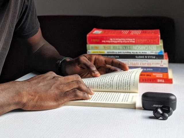a man reading a book with a pile of books