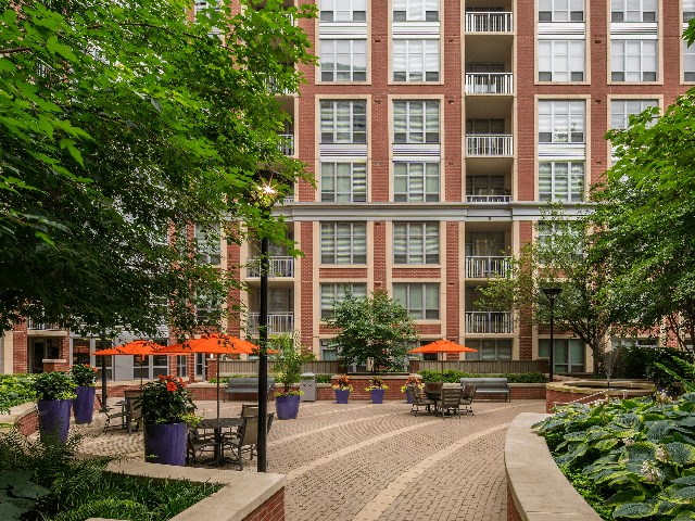 a courtyard with tables and umbrellas in front of a building
