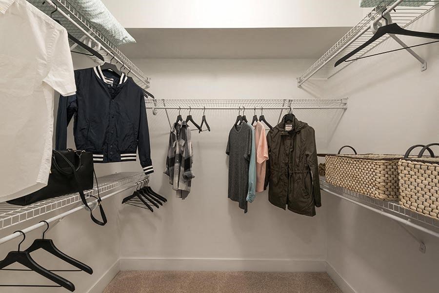 a walk in closet with jackets and clothes hanging on a rack