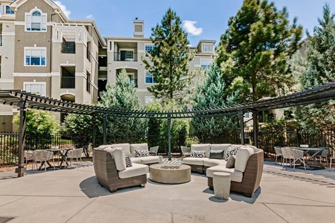 a patio with couches and tables in front of an apartment building